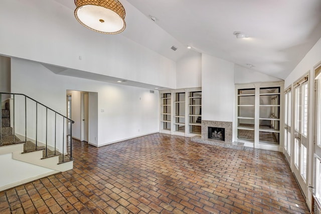 7628 Del Monte Dr, Houston, TX 77063 - unfurnished living room featuring brick floor, high vaulted ceiling, visible vents, and stairway