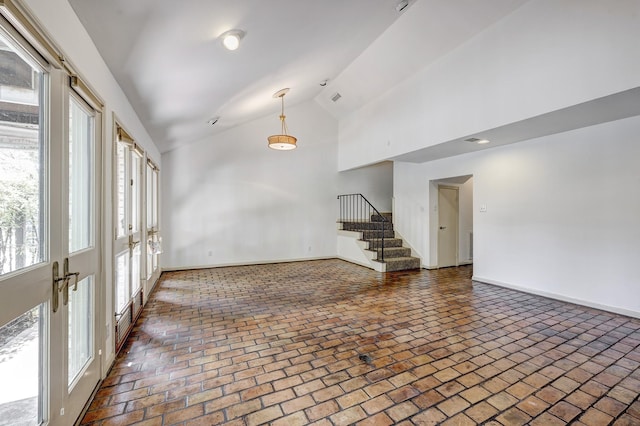 7628 Del Monte Dr, Houston, TX 77063 - unfurnished living room with baseboards, high vaulted ceiling, brick floor, and stairway