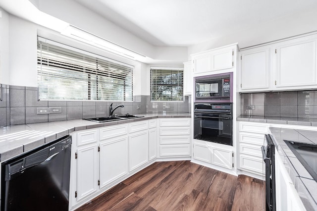 kitchen featuring a sink, black appliances, white cabinetry, and decorative backsplash