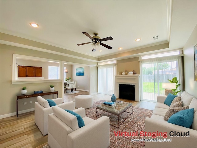 living room with a fireplace with flush hearth, light wood finished floors, baseboards, and a ceiling fan