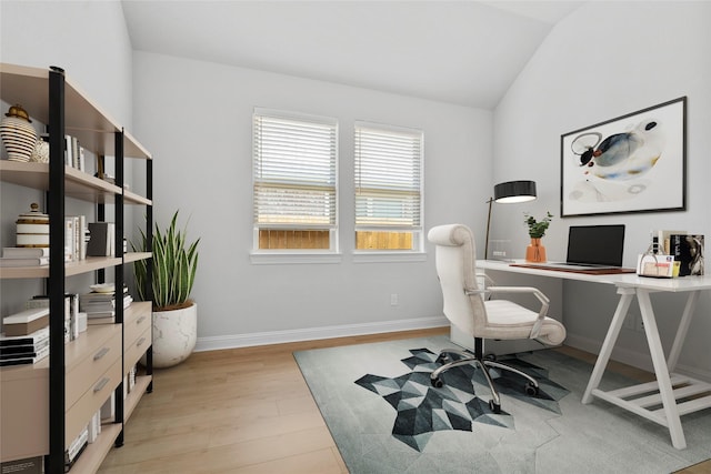 home office with baseboards, light wood-style floors, and vaulted ceiling