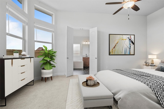 bedroom featuring light colored carpet, ensuite bath, and baseboards