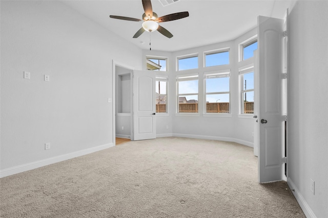 spare room with baseboards, a ceiling fan, and light carpet