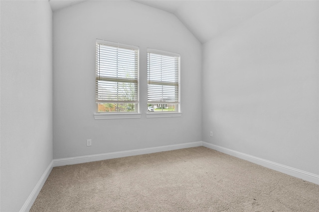 spare room with carpet flooring, baseboards, and lofted ceiling