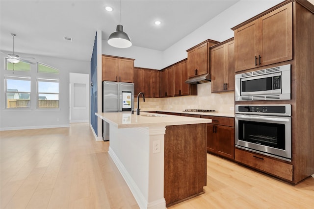 kitchen featuring a sink, appliances with stainless steel finishes, a ceiling fan, under cabinet range hood, and backsplash