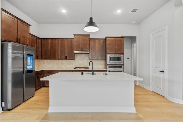 kitchen featuring light wood-style floors, visible vents, appliances with stainless steel finishes, light countertops, and a sink