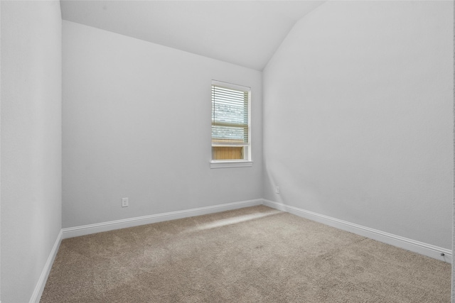 empty room with baseboards, vaulted ceiling, and carpet floors
