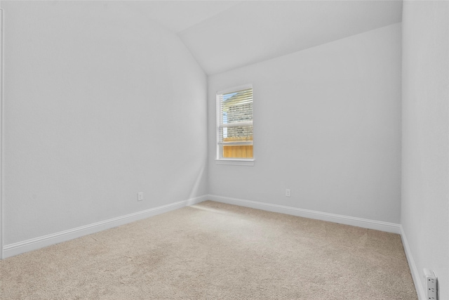 empty room with baseboards, light colored carpet, and lofted ceiling