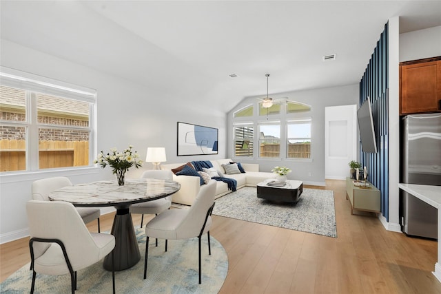 dining space featuring light wood-type flooring, baseboards, a ceiling fan, visible vents, and lofted ceiling