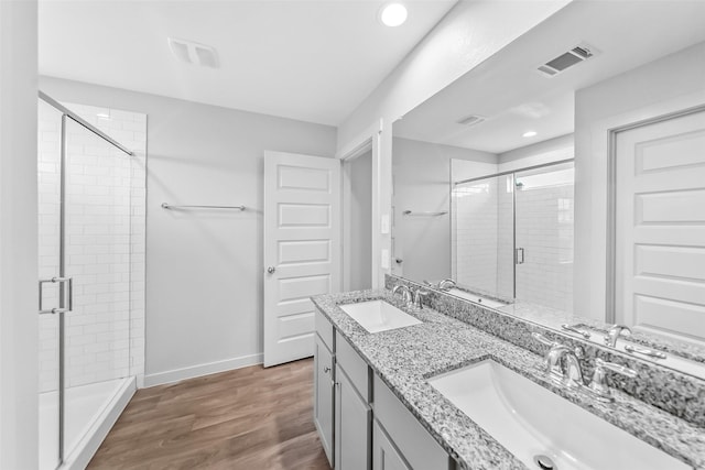 full bath with a stall shower, wood finished floors, recessed lighting, baseboards, and double vanity