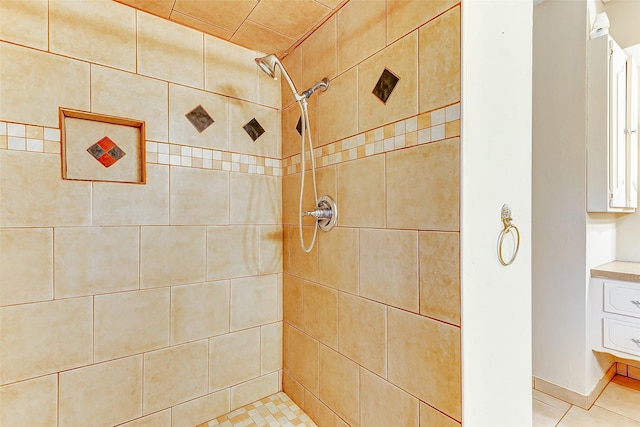 full bath featuring tiled shower and tile patterned flooring