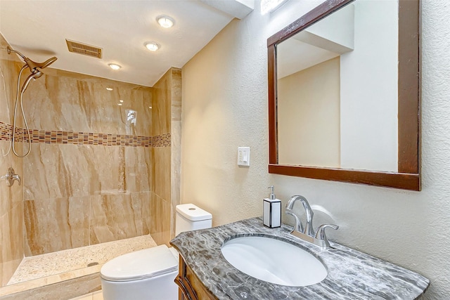 bathroom featuring toilet, a stall shower, a textured wall, and visible vents