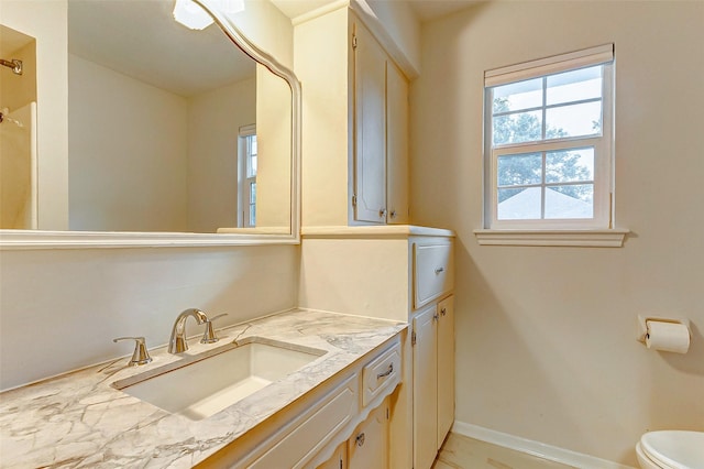 bathroom featuring toilet, baseboards, marble finish floor, and vanity