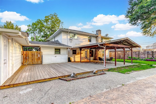 back of property with fence, a wooden deck, and a chimney