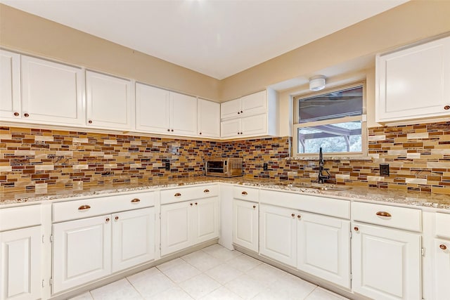 kitchen with decorative backsplash, a sink, and white cabinetry