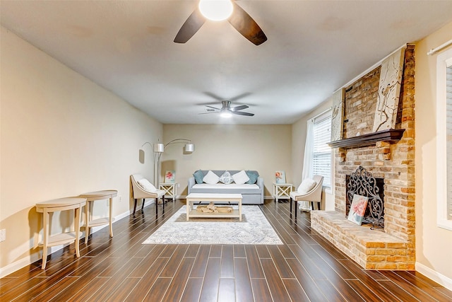 living area with a fireplace, dark wood-type flooring, baseboards, and ceiling fan