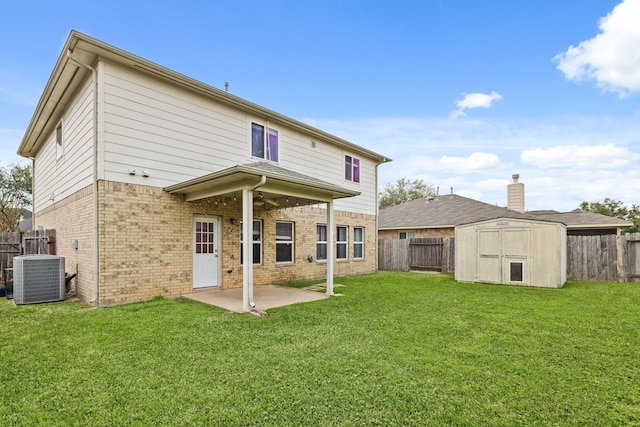 back of property featuring central AC unit, a fenced backyard, brick siding, and a yard