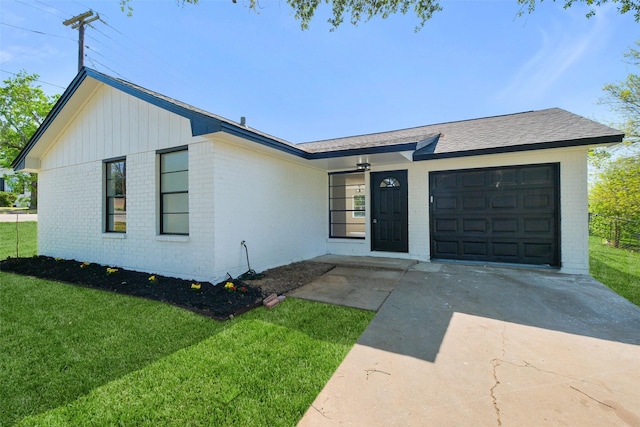 view of front of home featuring a front yard, an attached garage, brick siding, and driveway