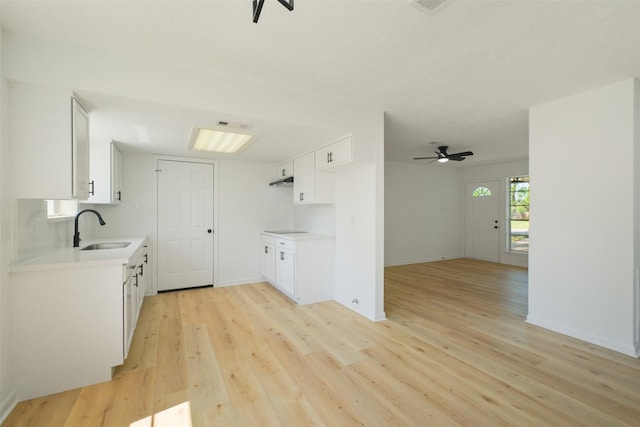 kitchen with a sink, light countertops, a ceiling fan, and light wood finished floors