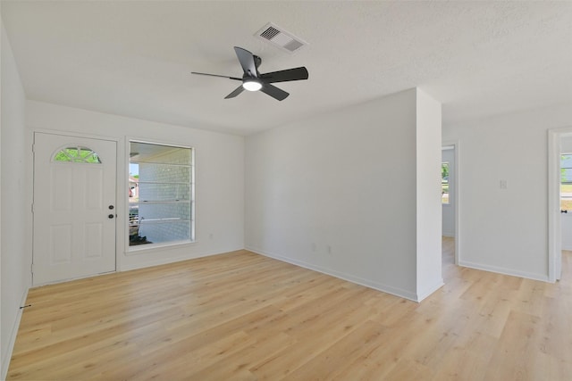 foyer entrance featuring visible vents, ceiling fan, light wood-type flooring, and baseboards