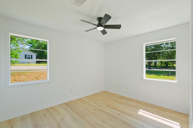 unfurnished room featuring visible vents, a wealth of natural light, light wood-style floors, and baseboards