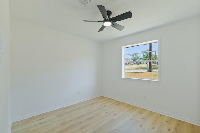 spare room with wood finished floors, ceiling fan, baseboards, and visible vents
