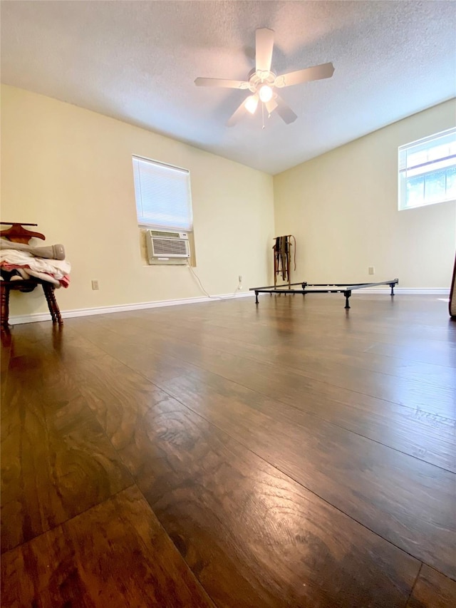 empty room featuring a textured ceiling, baseboards, dark wood-style floors, and ceiling fan