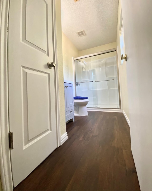 hallway featuring visible vents, a textured ceiling, and dark wood finished floors