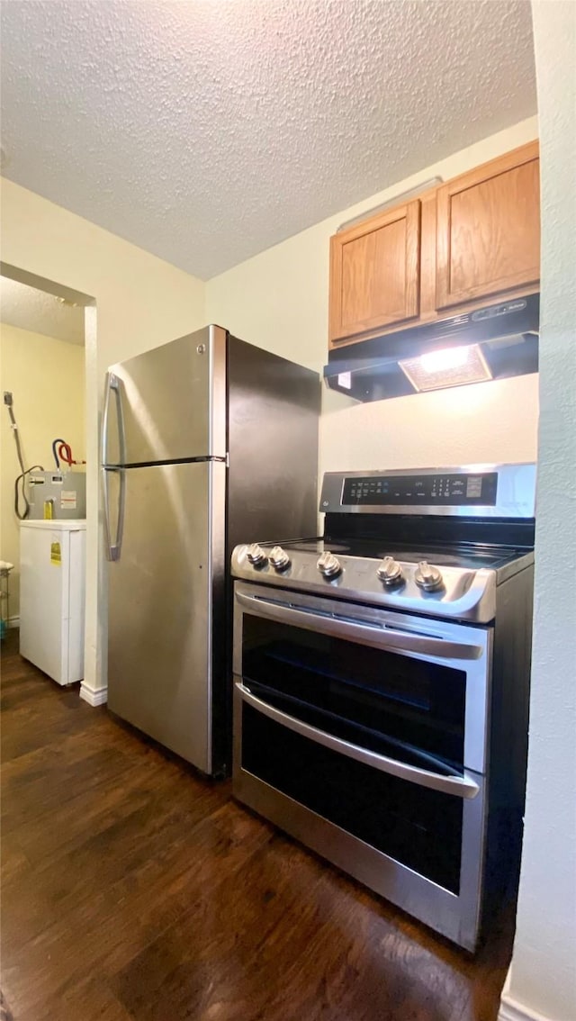 kitchen featuring washer / dryer, dark wood-style floors, a textured ceiling, under cabinet range hood, and appliances with stainless steel finishes