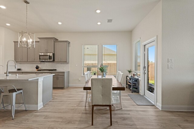 interior space with gray cabinetry, stainless steel microwave, a sink, and a notable chandelier