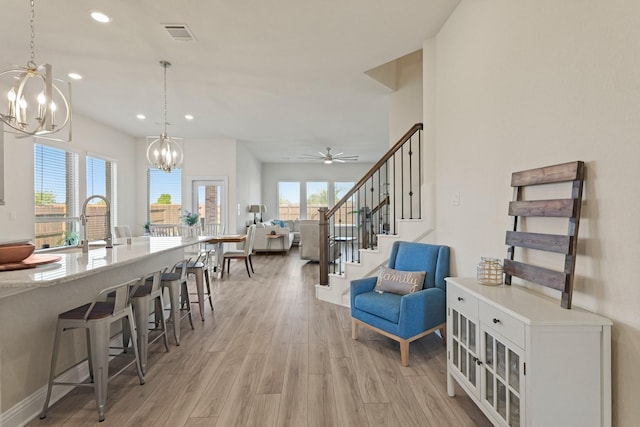 interior space featuring visible vents, stairway, ceiling fan with notable chandelier, light wood-style floors, and recessed lighting
