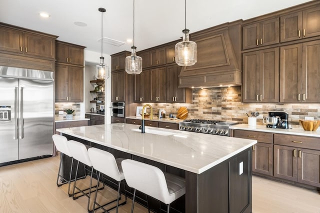 14127 Coyote Pointe Dr, Cypress, TX 77433 - kitchen with stainless steel appliances, tasteful backsplash, light wood-style flooring, a breakfast bar area, and premium range hood