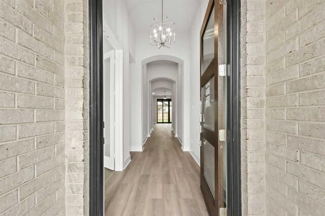 15615 Broadway Bnd, Conroe, TX 77302 - hallway featuring arched walkways, baseboards, an inviting chandelier, and wood finished floors