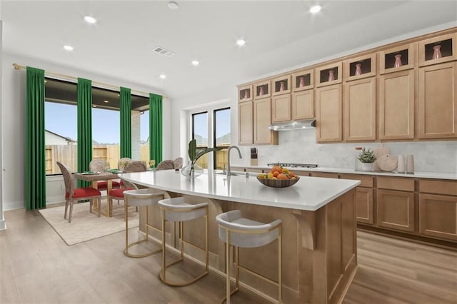 15615 Broadway Bnd, Conroe, TX 77302 - kitchen with a kitchen bar, visible vents, light countertops, stainless steel gas stovetop, and light wood-style flooring