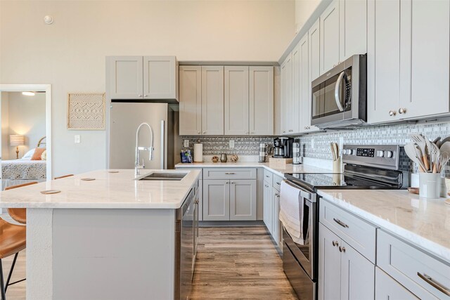 206 Damar Cv, Canyon Lake, TX 78133 - kitchen with light stone countertops, a kitchen bar, appliances with stainless steel finishes, a kitchen island with sink, and decorative backsplash