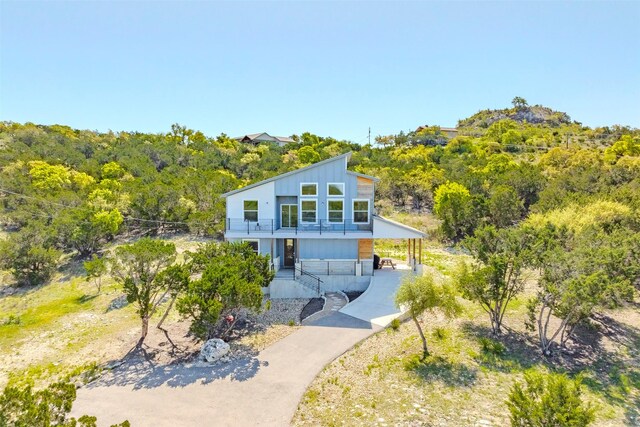 206 Damar Cv, Canyon Lake, TX 78133 - view of front facade featuring a carport, a view of trees, a balcony, and aphalt driveway
