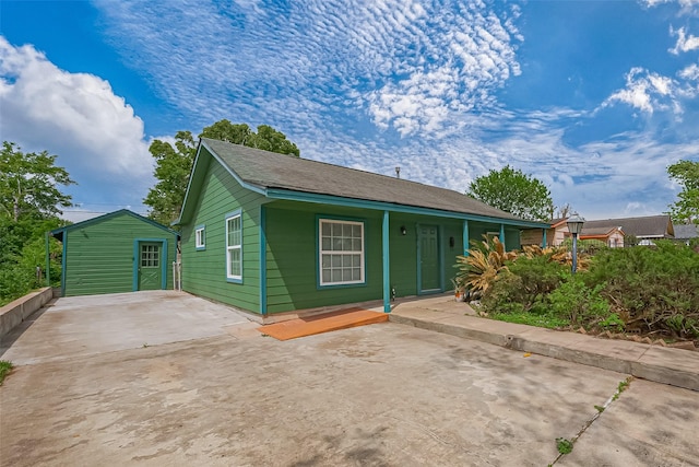 bungalow with a porch, an outdoor structure, and driveway