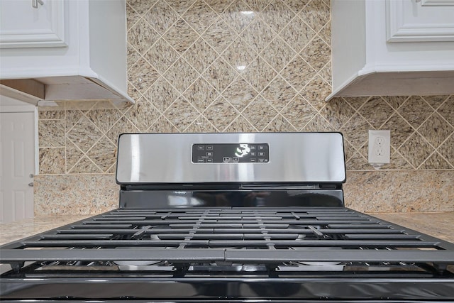 room details featuring gas stove, light countertops, backsplash, and white cabinets