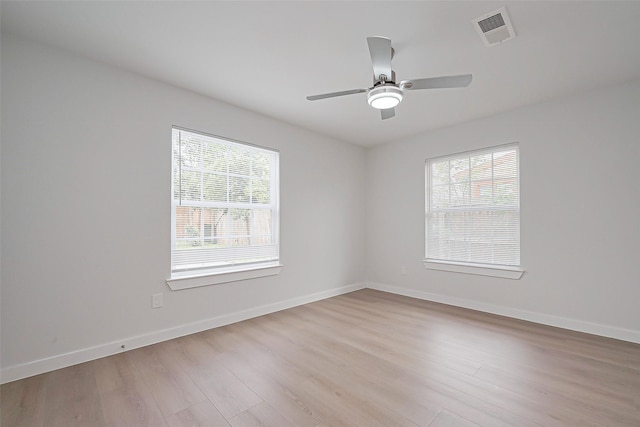 unfurnished room featuring wood finished floors, baseboards, visible vents, and a wealth of natural light