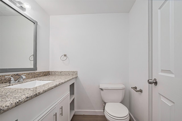 bathroom with toilet, baseboards, vanity, and wood finished floors
