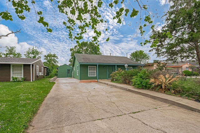 ranch-style house with concrete driveway, a front yard, an outdoor structure, and fence