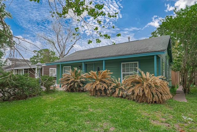ranch-style home featuring a porch, roof with shingles, and a front yard