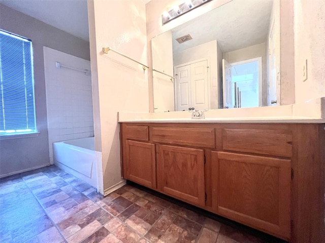 full bathroom featuring stone finish floor, vanity, baseboards, and visible vents