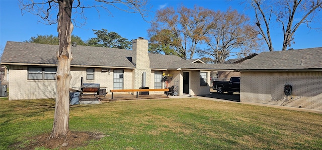 rear view of house with brick siding, cooling unit, a yard, and a chimney