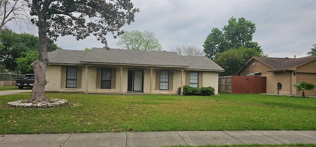 ranch-style house with brick siding, a front lawn, and fence