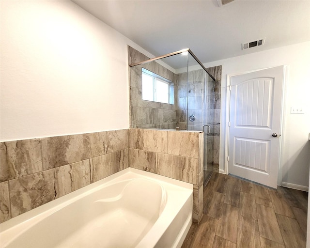 full bathroom with visible vents, a bath, a stall shower, and wood finished floors