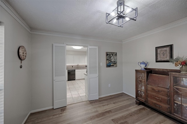 interior space with baseboards, light wood-type flooring, a textured ceiling, and crown molding
