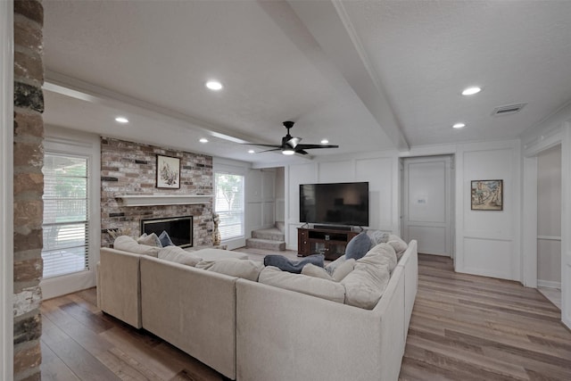 living area with a decorative wall, wood finished floors, a fireplace, and recessed lighting