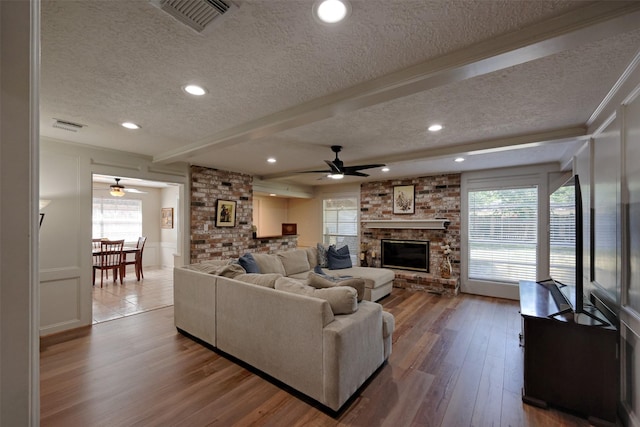 living area featuring visible vents, a textured ceiling, and ceiling fan