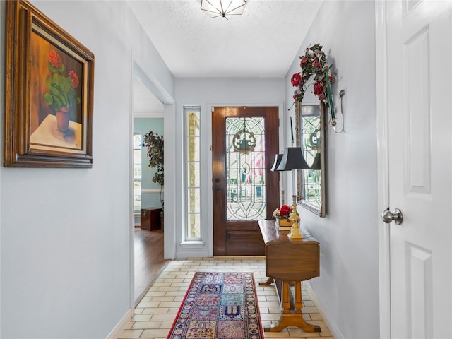 foyer featuring baseboards and a textured ceiling